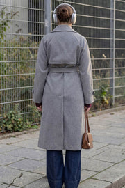 Abrigo largo de doble cruce de botón en contraste, manga larga con trabilla y botón en puños, con solapa, bata decorativa frontal, bolsillos delanteros con vivos, trabillas y cinturón amarrable del mismo tejido.