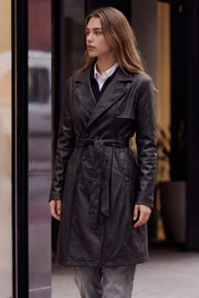 Abrigo trench de efecto piel, fit recto, con solapa, bolsillos delanteros con vivos, detalle de bata delantera y manga larga. Trabillas, cinturón amarrable del mismo tejido y cierre frontal con doble cruce de botón.