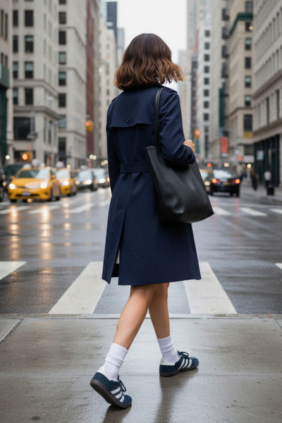 Abrigo trench corto de fit recto, con cuello solapa, bolsillos delanteros con vivos, detalle de bata trasera y manga larga. Trabillas, cinturón amarrable del mismo tejido y cierre frontal con doble cruce de botones en contraste. Detalle de trabilla y botón en hombros, bata trasera, cuello y puños.