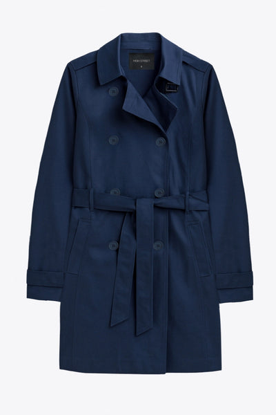 Abrigo trench corto de fit recto, con cuello solapa, bolsillos delanteros con vivos, detalle de bata trasera y manga larga. Trabillas, cinturón amarrable del mismo tejido y cierre frontal con doble cruce de botones en contraste. Detalle de trabilla y botón en hombros, bata trasera, cuello y puños.