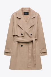 Abrigo trench corto de fit recto, con solapa, bolsillos delanteros con vivos, detalle de bata frontal con botón decorativo y trasera. Manga larga con trabilla en puños, cinturón amarrable del mismo tejido y cierre frontal con doble cruce de botones en contraste.