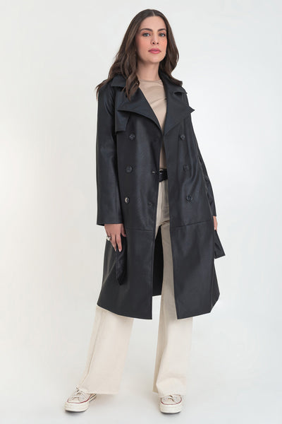 Abrigo trench largo de efecto piel, fit recto, manga larga, con solapa y bata en espalda, cortes decorativos frontales, trabillas y cinturón del mismo tejido con hebilla en contraste. Cierre frontal con doble cruce de botones en contraste.