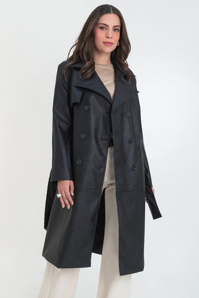 Abrigo trench largo de efecto piel, fit recto, manga larga, con solapa y bata en espalda, cortes decorativos frontales, trabillas y cinturón del mismo tejido con hebilla en contraste. Cierre frontal con doble cruce de botones en contraste.