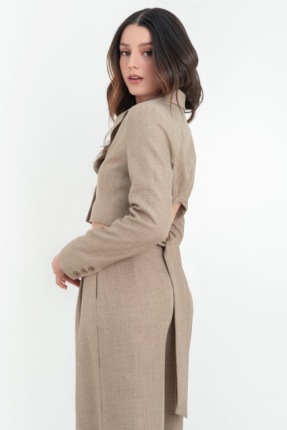 Blazer corto de fit ajustado, hombreras y solapa, manga larga y cierre frontal con botones. Detalle de cut out en espalda con rib elástico y lazo inferior amarrable.