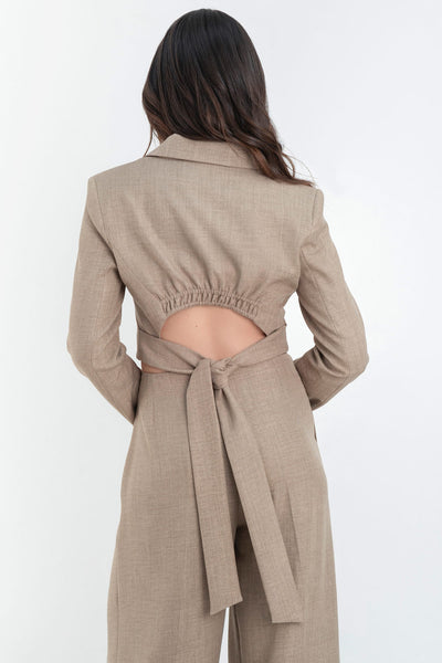 Blazer corto de fit ajustado, hombreras y solapa, manga larga y cierre frontal con botones. Detalle de cut out en espalda con rib elástico y lazo inferior amarrable.