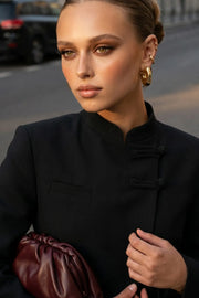 Blazer corto cruzado de manga larga con abertura en puños, cuello mao, vivo decorativo frontal, detalle de botones decorativos frontales y bajo curveado.