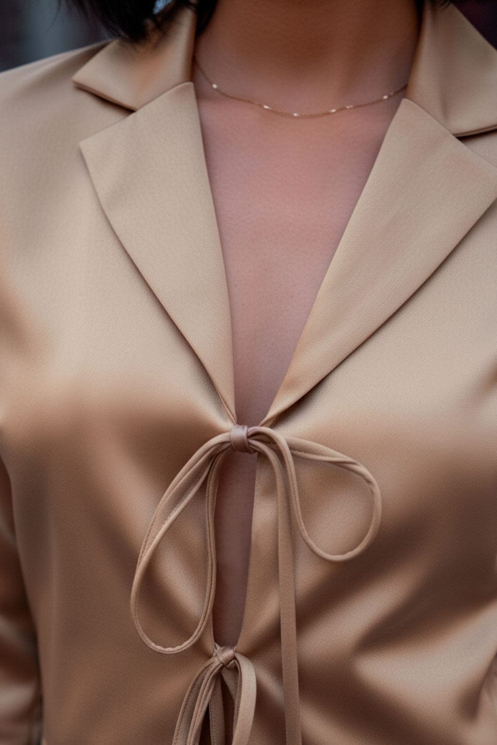 Blazer corto satinado de fit recto, manga larga, con solapa y cierre frontal con doble lazo amarrable.