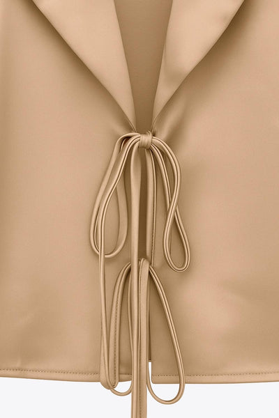 Blazer corto satinado de fit recto, manga larga, con solapa y cierre frontal con doble lazo amarrable.