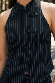 Blusa corta de lino, fit recto, estampado rayas, sin mangas, cuello mao y cierre frontal con botones pankou. Detalle de abertura frontal con bajo curveado.