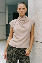 Blusa fluida de manga corta seguida, cuello mock seguido con plisados decorativos en hombro y cuello. Cierre posterior con botones y ojales.
