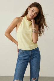 Blusa corta de lino, fit fluido, sin mangas, cuello halter fluido con plisados, escote en espalda y lazo amarrable posterior. Cierre posterior con botón y ojal.