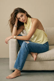 Blusa corta de lino, fit fluido, sin mangas, cuello halter fluido con plisados, escote en espalda y lazo amarrable posterior. Cierre posterior con botón y ojal.