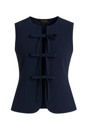 Blusa de fit ajustado, cuello redondo, sin mangas y cierre frontal con lazos amarrables. Detalle de bajo curveado frontal.