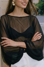 Blusa corta traslúcida de fit fluido, cuello barco y manga larga abullonada con rib elástico en puños.