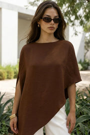 Blusa tipo túnica asimétrica, de cuello redondo, con hombreras, manga corta seguida, fit fluido y bajo asimétrico.