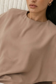 Blusa tipo túnica asimétrica, de cuello redondo, con hombreras, manga corta seguida, fit fluido y bajo asimétrico.