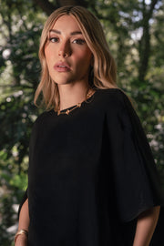 Blusa tipo túnica asimétrica, de cuello redondo, con hombreras, manga corta seguida, fit fluido y bajo asimétrico.