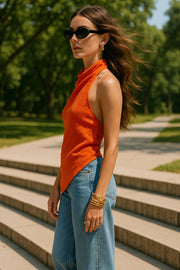 Blusa asimétrica de fit fluido, sin mangas, cuello halter fluido con plisados, escote en espalda y bajo frontal asimétrico. Cierre posterior con botón y ojal.