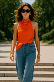 Blusa asimétrica de fit fluido, sin mangas, cuello halter fluido con plisados, escote en espalda y bajo frontal asimétrico. Cierre posterior con botón y ojal.