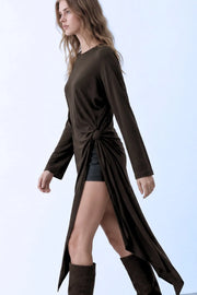 Blusa larga de fit fluido, cuello barco, manga larga amplia, bajo asimétrico, plisados en costado con abertura y nudo decorativo, cierre posterior con botón y ojal.