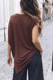 Blusa de fit fluido, cuello barco, manga corta seguida y bajo asimétrico diagonal.