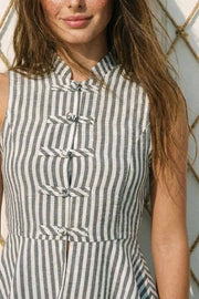 Blusa de fit ajustado, estampado rayas, cuello mao, sin mangas, pinzas frontales y peplum con olanes en bajo. Cierre frontal con botones alamares.