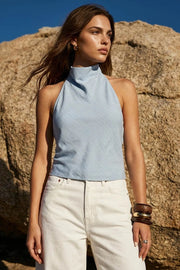 Blusa de estampado rayas, cuello halter fluido, escote en espalda con lazo amarrable posterior, cierre con botón y ojal.