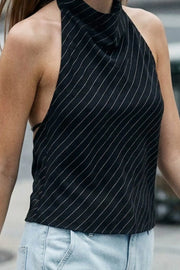 Blusa de estampado rayas, cuello halter fluido, escote en espalda con lazo amarrable posterior, cierre con botón y ojal.