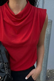 Blusa de fit amplio, sin mangas y cuello alto con detalles plisados en hombros. Cierre posterior con botón y ojal.