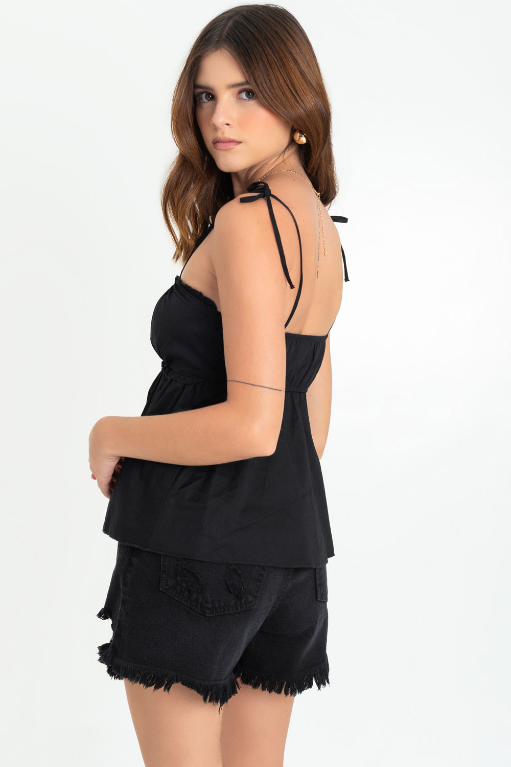 Blusa corta de fit fluido, tirantes delgados con nudo amarrable, escote v redondeado con cortes decorativos, plisados y olanes en bordes. Detalle de rib elástico posterior.