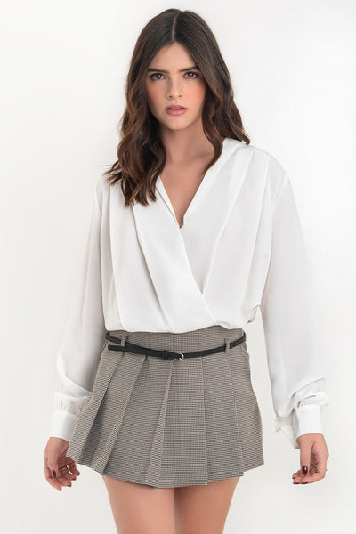 Blusa corta de fit fluido, escote v cruzado, manga larga abullonada con puño abotonado, plisados en hombros y bajo con rib elástico.