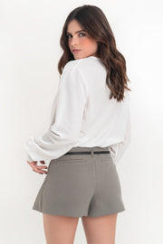 Blusa corta de fit fluido, escote v cruzado, manga larga abullonada con puño abotonado, plisados en hombros y bajo con rib elástico.