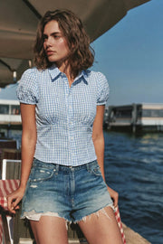 Camisa corta de estampado cuadros, fit recto, manga corta abullonada con rib elástico en bordes, cuello camisero, cortes y plisados frontales. Cierre frontal con hilera de botones.