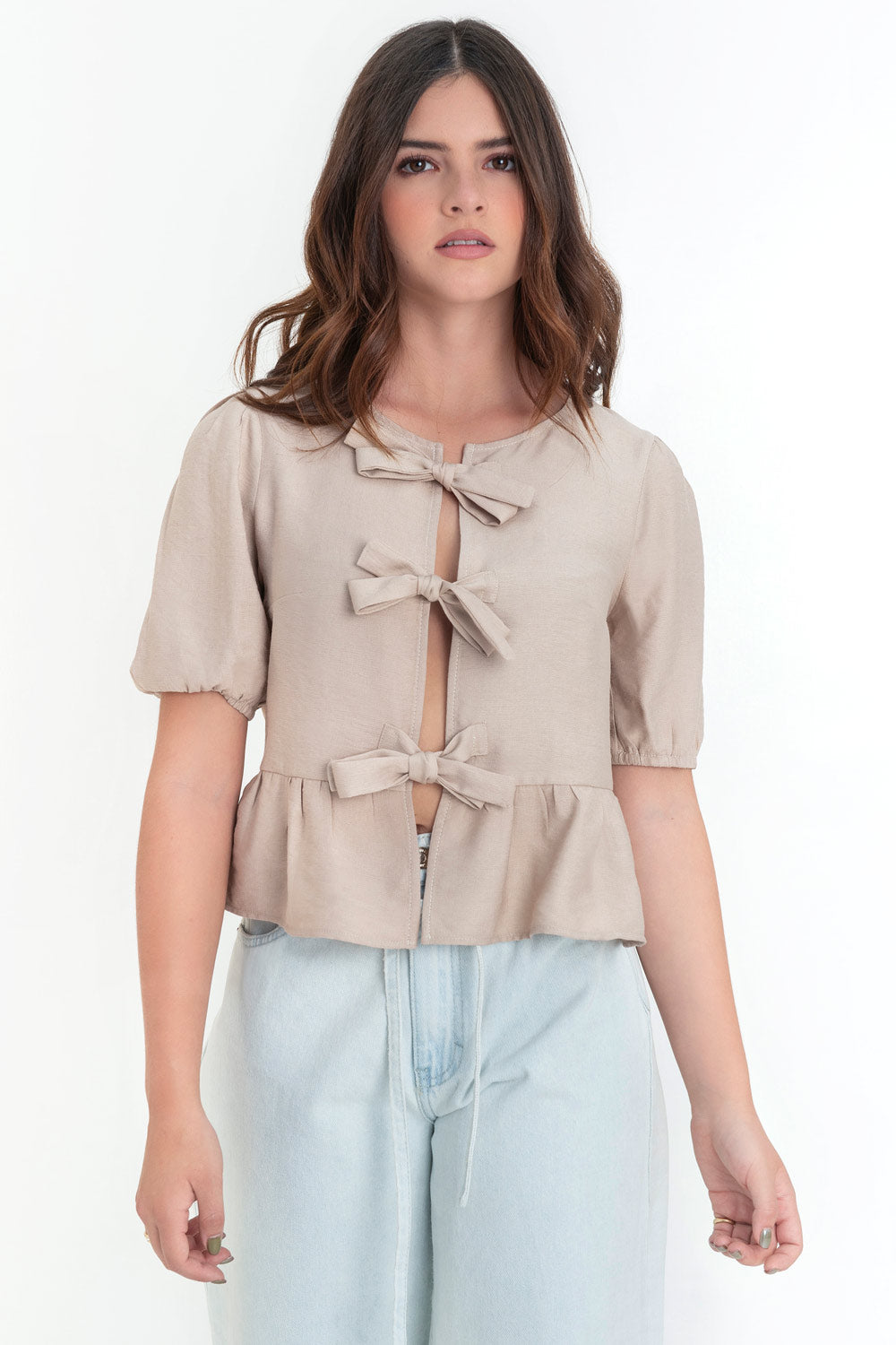 Blusa de manga corta abullonada con rib elástico en bordes, cuello redondo y cierre frontal con lazos amarrables. Detalle de peplum con olanes en bajo.