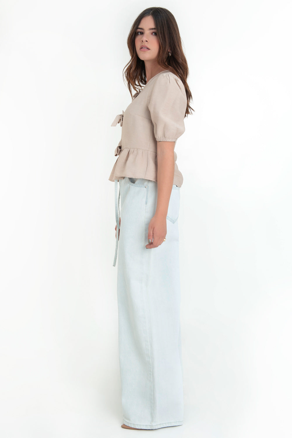 Blusa de manga corta abullonada con rib elástico en bordes, cuello redondo y cierre frontal con lazos amarrables. Detalle de peplum con olanes en bajo.