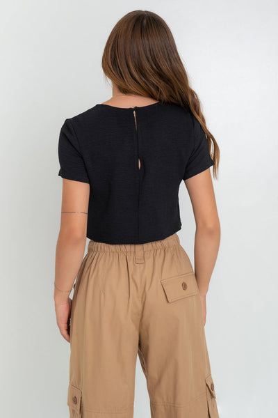 Blusa corta de fit ligeramente oversized, de cuello redondo, manga corta y cierre posterior con botón y ojal.