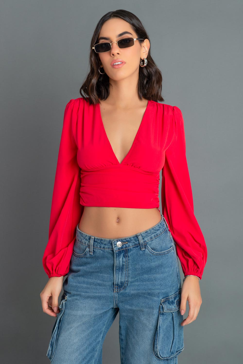 Blusa corta de manga larga abullonada, escote v con detalles plisados, cortes frontales y plisados en costados.