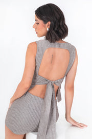 Blusa corta ajustada de estampado rayas, sin mangas, cuello redondo, corte en a, pinzas frontales y cut out en espalda con lazo amarrable posterior. Cierre posterior con botón y ojal.