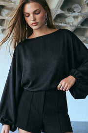 Blusa de fit fluido, cuello barco y manga larga abullonada con rib elástico en puños.