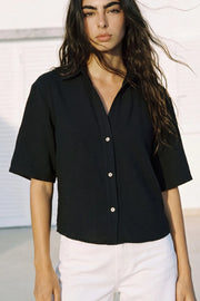 Camisa corta de fit recto, manga corta, cuello solapa, escote v y cierre frontal con hilera de botones.