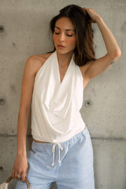 Blusa de cuello halter, escote fluido frontal, sin mangas y escote en espalda.