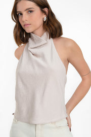 Blusa halter de fit fluido, sin mangas, cuello halter fluido con plisados y escote en espalda. Cierre posterior con botón y ojal.