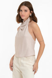 Blusa halter de fit fluido, sin mangas, cuello halter fluido con plisados y escote en espalda. Cierre posterior con botón y ojal.