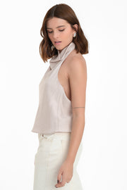 Blusa halter de fit fluido, sin mangas, cuello halter fluido con plisados y escote en espalda. Cierre posterior con botón y ojal.