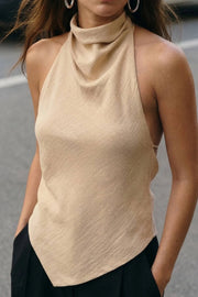 Blusa de fit fluido, sin mangas, cuello halter fluido con plisados, escote en espalda y lazo amarrable posterior. Cierre posterior con botón y ojal. Detalle de bajo frontal asimétrico.