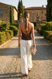 Blusa corta de fit fluido, sin mangas, estampado rayas, cuello halter fluido con plisados, escote en espalda y lazo amarrable posterior. Cierre posterior con botón y ojal.