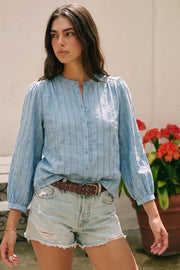 Camisa de fit fluido, estampado rayas, manga larga globo con puño abotonado, cuello mao, plisados frontales y posteriores. Cierre frontal con hilera de botones.