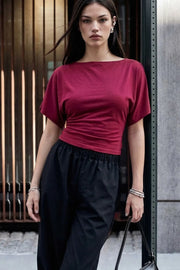 Blusa corta de fit ajustado, cuello barco, manga corta seguida con olanes y nudo amarrable posterior.