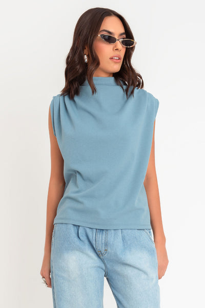 Blusa de fit oversized, sin mangas y cuello alto con detalles plisados en hombros.