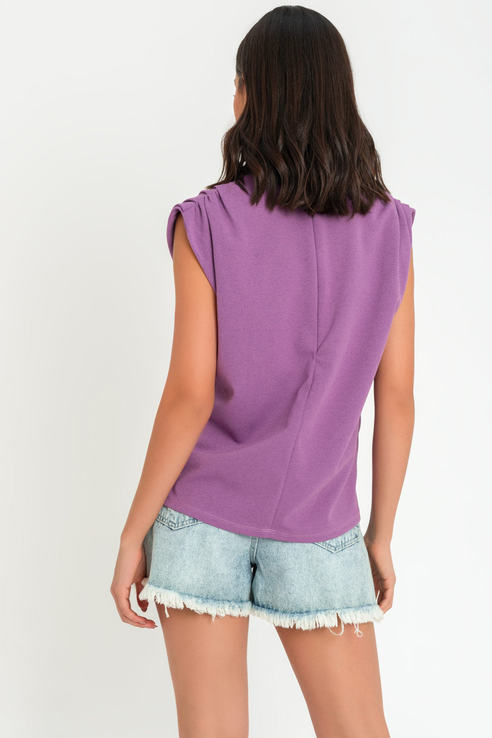 Blusa de fit oversized, sin mangas y cuello alto con detalles plisados en hombros.